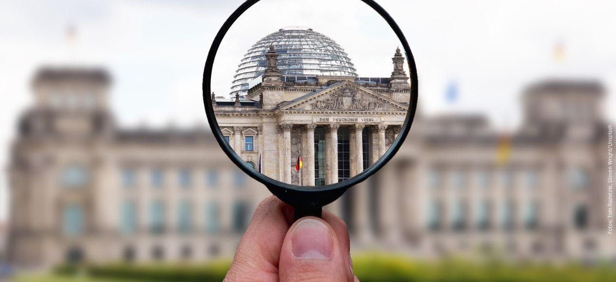 Eine Lupe vergrößert das Bundestagsgebäude